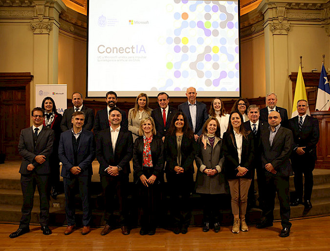 Grupo de directivos de la UC y Microsoft, en un salón de la UC, con la presentación de ConectIA de fondo.