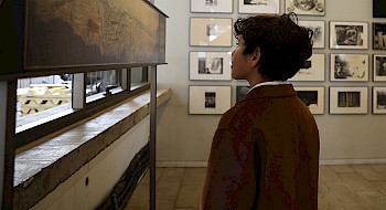 Niño observa una obra, al fondo se observa un muro con cuadros.