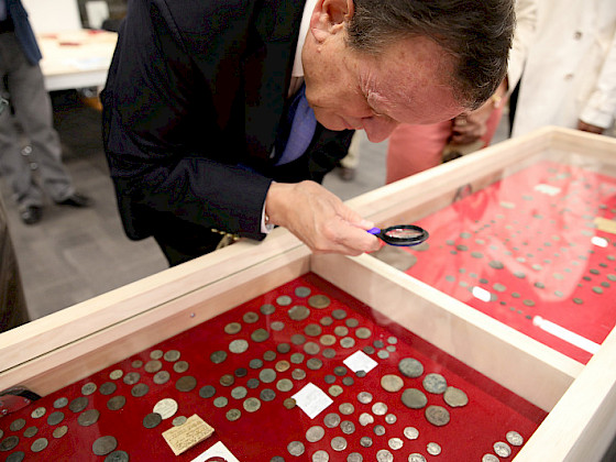 Rector Ignacio Sánchez mirando una colección de monedas.
