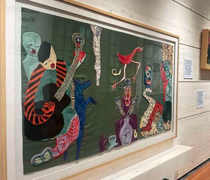 Exposición de Violeta Parra en que se ve uno de sus cuadros colgado en la pared.