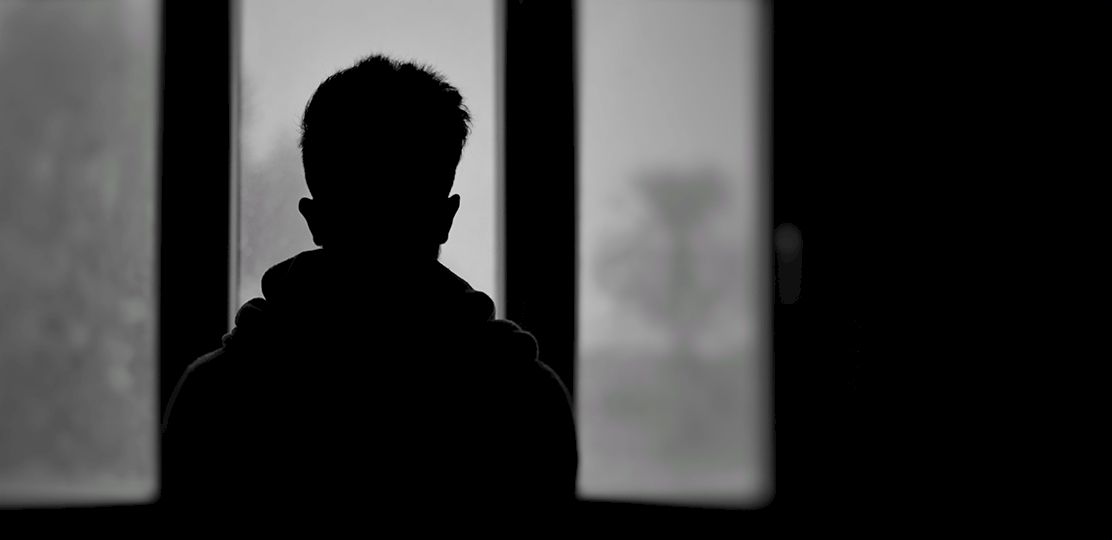Silueta de un niño de espaldas a una ventana