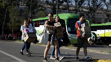 Grupo de jóvenes sorientes llevando cajas hacia los buses.