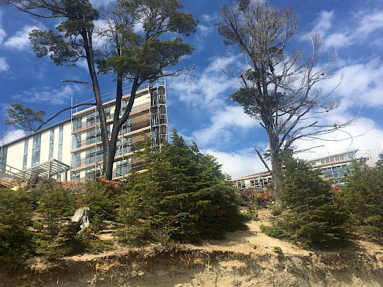 Cerro con árboles, detrás de estos dos edificios.