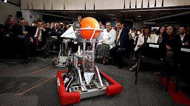 Imagen de un robot y personas de la UC mirándolo