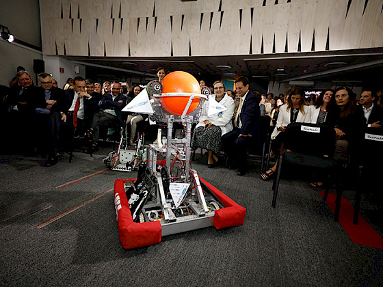 Imagen de un robot y personas de la UC mirándolo