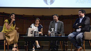 La foto muestra el escenario con el panel en el que participaron el alcalde de Puente Alto, Germán Codina, la alcaldesa de Peñalolén, Carolina Leitao y el alcalde de Macul, Gonzalo Montoya. Ellos además de la moderadora Angélica Bulnes, periodista de Tele13 Radio.