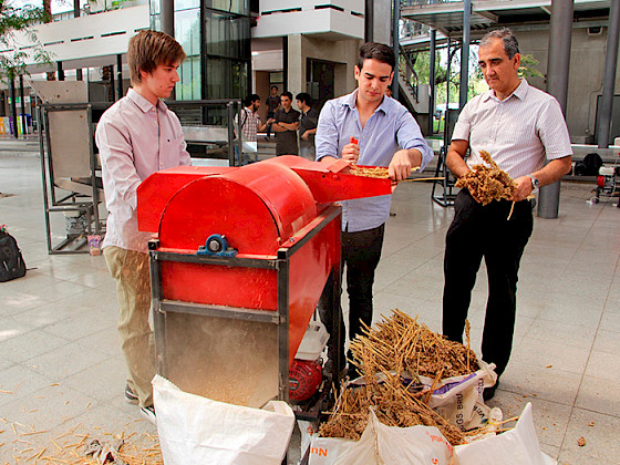 La imagen muestra dos alumnos y al decano Rodrigo Figueroa junto a una máquina trilladora