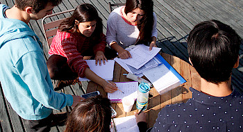 Imagen de alumnos estudiando alrededor de una mesa.