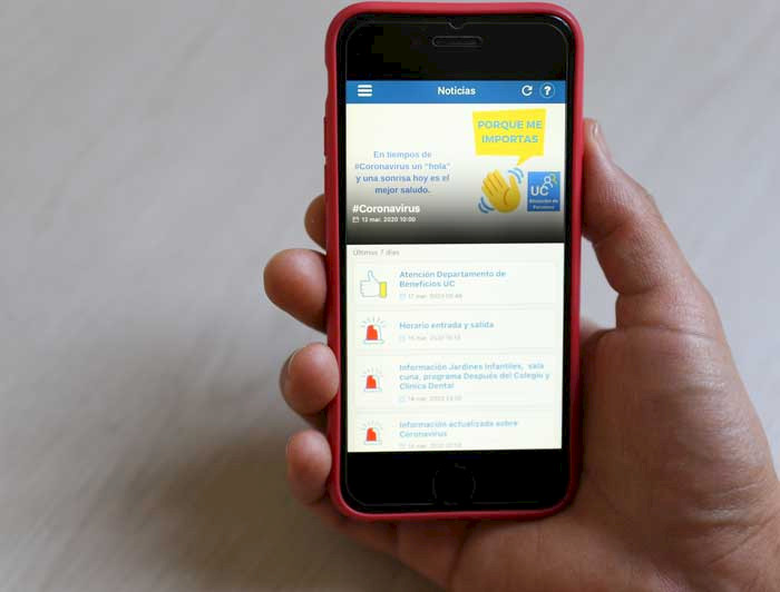 Foto de mano sosteniendo un teléfono celular en cuya pantalla aparece la aplicación Personas UC