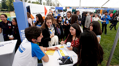 Foto de estudiantes haciendo consultas por carreras en feria.