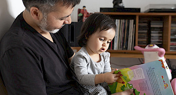 Padre con hija revisan libro infantil