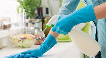 Se muestra persona limpiando una superficie de una mesa de cocina.