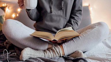 Persona sentada que tiene sobre sus piernas un libro abierto