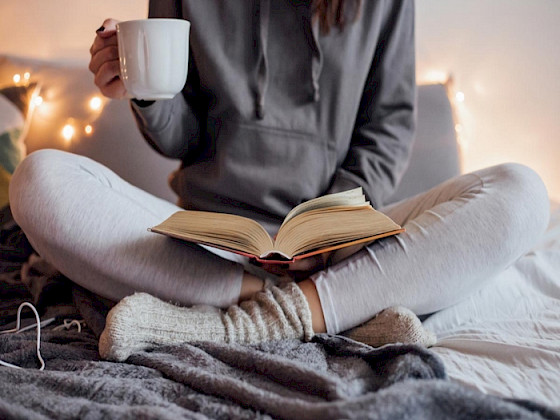 Persona sentada que tiene sobre sus piernas un libro abierto