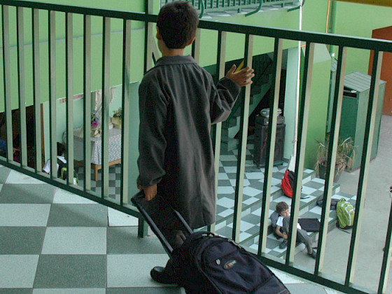 Escolar con cotona mirando el patio desde el segundo piso.