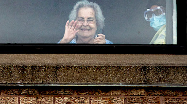 Mujer de la 3a edad saluda desde la ventana.