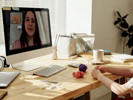 imagen de computador con profesora enseñando por medio de la pantalla a un niño