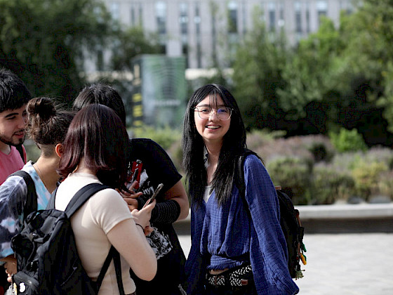 Estudiantes UC conversando, una de ellas mira hacia la cámara sonriendo.