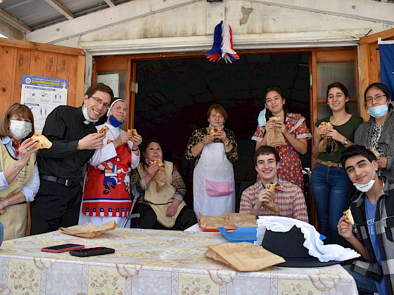 Personas en el comedor social comiendo empanadas