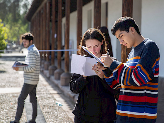 Jovenes leyendo unos papeles de pie