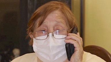 Mujer mayor con mascarilla hablando por celular.