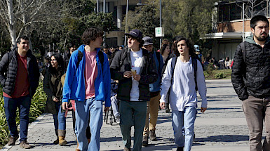 Jóvenes caminan en patio de campus universitario.