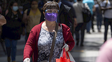 Mujer con mascarilla y escudo facial caminando por las calles del centro De Santiago.