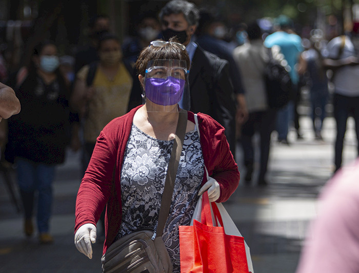 Mujer con mascarilla y escudo facial caminando por las calles del centro De Santiago.
