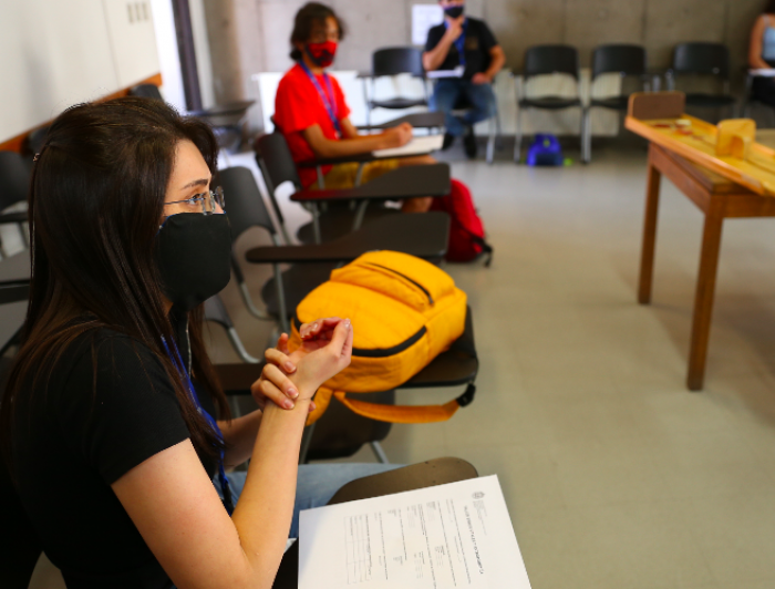 alumnos sentados en sillas dentro de una sala de clases, usando mascarilla