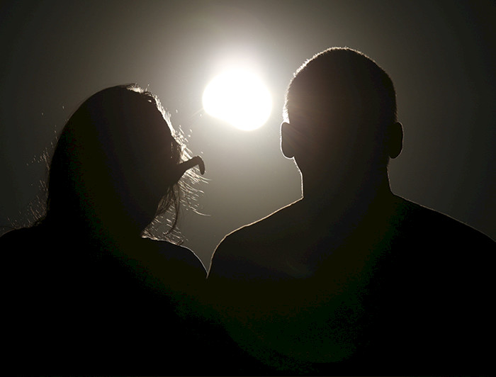 a man and woman are silhouetted in front of a solar eclipse