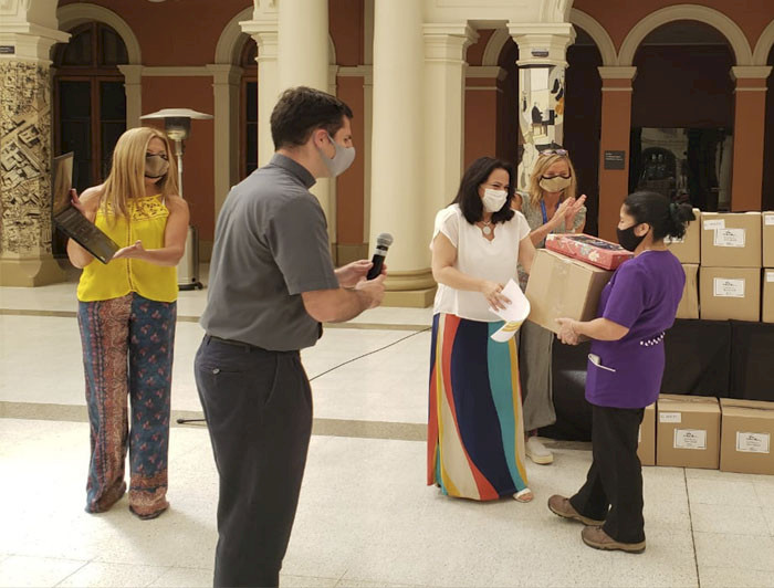 Foto donde se ven cinco personas, una de ellas recibiendo una caja