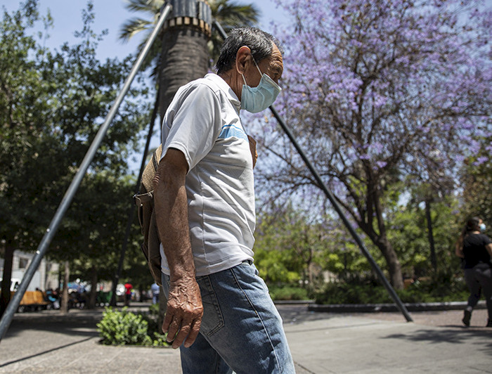 Hombre adulto mayor camina por el centro De Santiago con mascarilla.