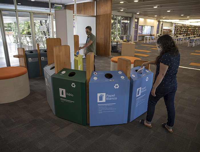 Foto que muestra receptáculos coloridos de reciclaje de papel y otros materiales en la biblioteca San Joaquín del campus homónimo.