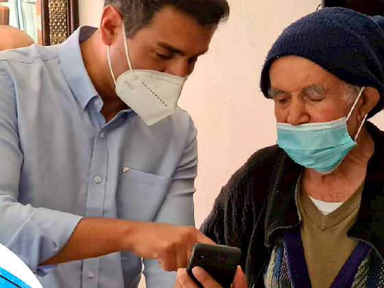 un hombre adulto y una mujer adulta mayor, él le está entregando un celular