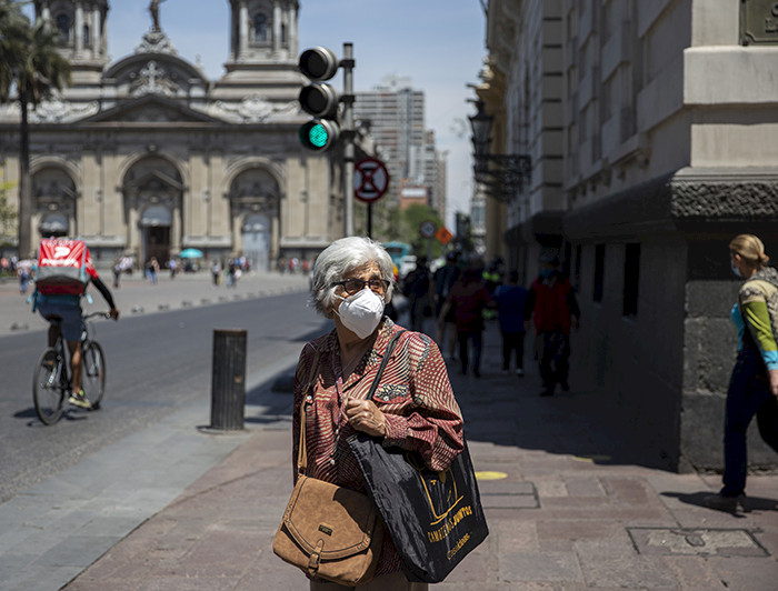 Persona mayor con mascarilla detenida en la calle y de fondo se ve la Catedral Metropolitana