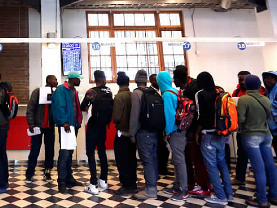 Migrantes de color en fila para obtener documentos.