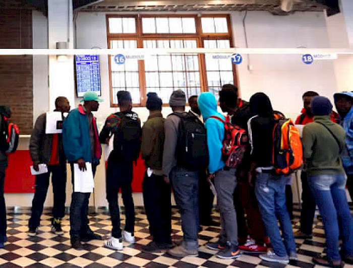 Migrantes de color en fila para obtener documentos. 