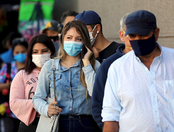 a group of people wearing face masks are standing in line