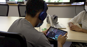 Joven del Sename enfocado de espalda revisa un video en un aparato inteligente iPad.
