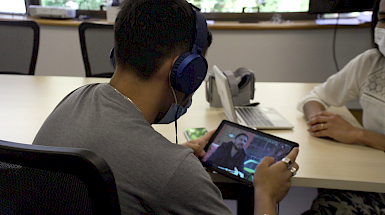Joven del Sename enfocado de espalda revisa un video en un aparato inteligente iPad.