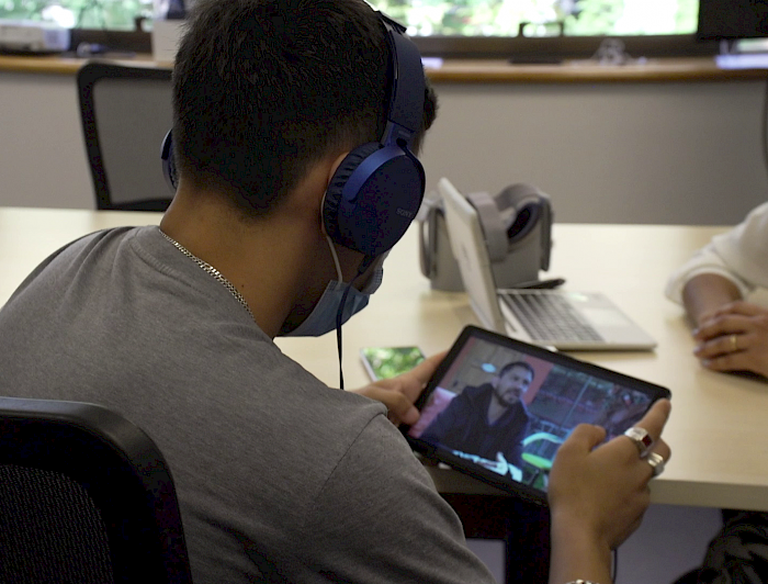 Joven del Sename enfocado de espalda revisa un video en un aparato inteligente iPad. 