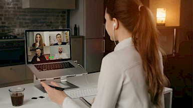 Alumna de cabello largo en sweater durante una reunión virtual con sus compañeros de universidad.