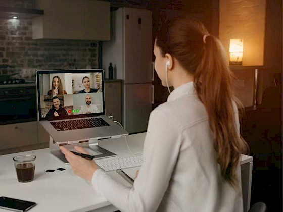 Alumna de cabello largo en sweater durante una reunión virtual con sus compañeros de universidad.