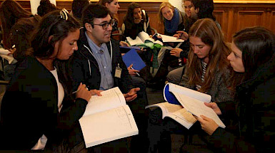 Image of a student orientation before the pandemic. Credits: César Cortés. Alt: Group of international students and a UC counselor in the Manuel José Yrarrázaval hall, Casa Central.