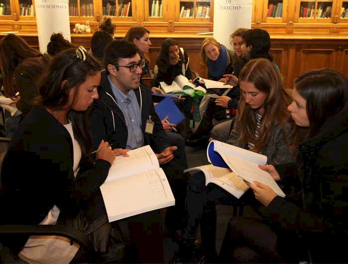 Image of a student orientation before the pandemic. Credits: César Cortés. Alt: Group of international students and a UC counselor in the Manuel José Yrarrázaval hall, Casa Central. 