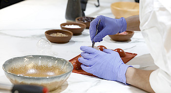 Una cocina hecha laboratorio donde aparece una mujer interviniendo alimentos.