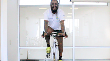 Profesor de deporte sobre una bicicleta estática en una clase virtual.