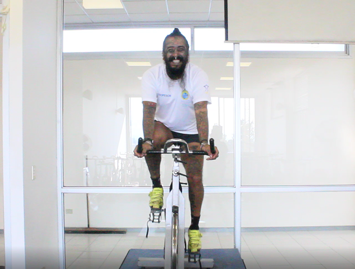 Profesor de deporte sobre una bicicleta estática en una clase virtual. 