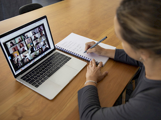 mujer frente a computador, anotando en cuaderno