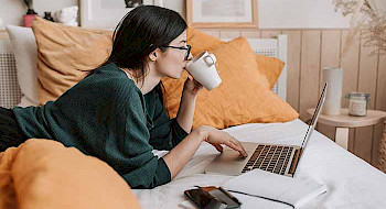 Imagen de mujer bebiendo café y estudiante frente a su computador.